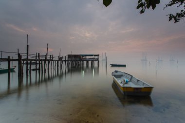 Bulutlu uzun pozlama gündoğumu iskeleye vurmuş. Görüntü içeren certai