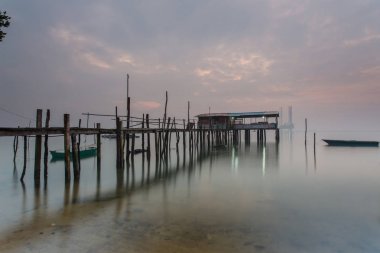 Bulutlu uzun pozlama gündoğumu iskeleye vurmuş. Görüntü içeren certai