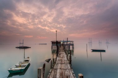 Bulutlu uzun pozlama gündoğumu iskeleye vurmuş. Görüntü içeren certai