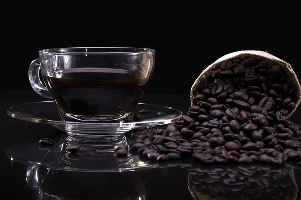 Une tasse de café avec des grains de café sur le fond noir — Photo