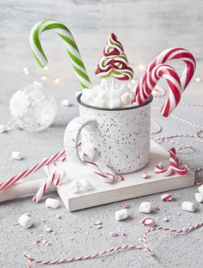 krema ve şeker kamışı ile kupa, Noel dekor gri arka plan üzerinde beyaz sıcak içecek close-up. Noel kavramı.