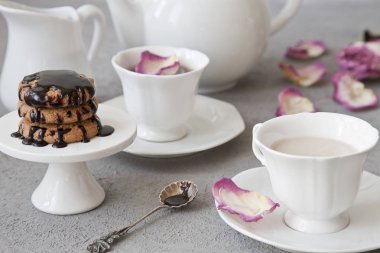 Beyaz fincan kahve süt ve çikolata Çerezler vintage tarzı arka planda masada çiçek yaprakları ile yakın çekim