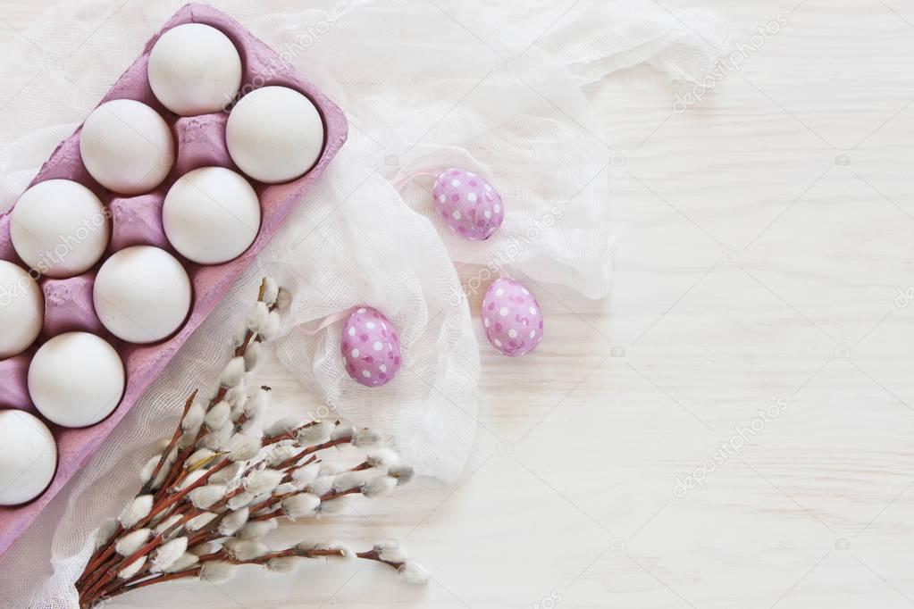 Close-up of white Easter eggs in pink paper box with white scarf on wooden table background with pussy-willow branches