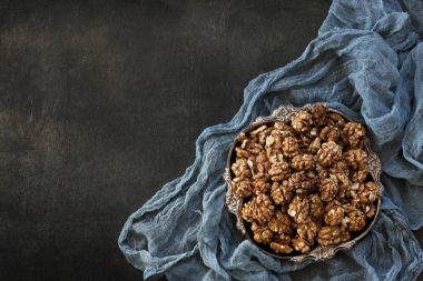 Close-up of a bowl with walnuts on black concreted background. Top view, background. clipart