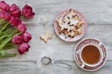 ev yapımı kelebek kurabiye yakın Lale çiçek ile gri ahşap antika arka plan üzerinde çay ile çekim 