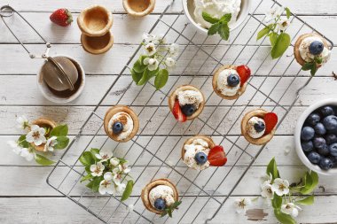Mascarpone peyniri, tarçın, çilek, yaban mersini ve güzel yabani elma ağacı dalları çiçeklenme ile ev yapımı kekler yakın çekim fotoğraf. Beyaz vintage ahşap zemin üzerinde Üstten Görünüm