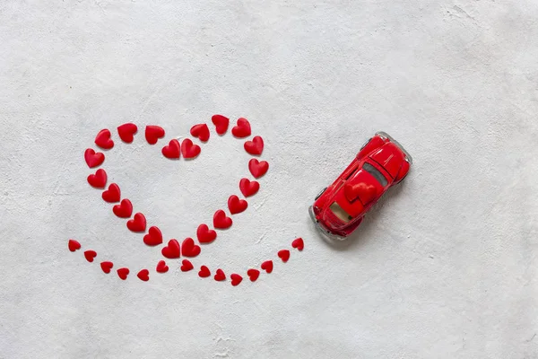 Heart shape made of small red hearts and a red toy car on a whit — 스톡 사진