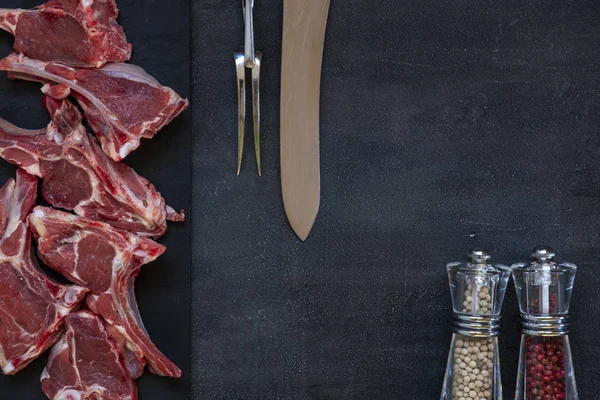 Costelas e temperos de carne de cordeiro fresca crua em fundo escuro — Fotografia de Stock