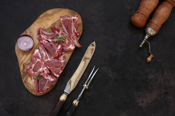 Costelas e temperos de carne de cordeiro fresca crua em fundo escuro — Fotografia de Stock