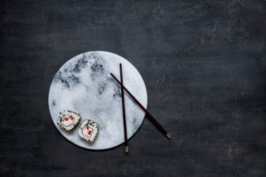 Japon krabbe mus suşisi Marbl Stone tahtasında yemek çubuklarıyla. Üst görünüm, siyah beton arkaplanı kapat