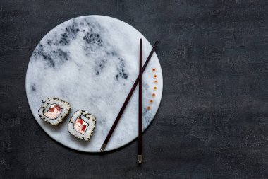 Japon krabbe mus suşisi, kırmızı havyarlı ve yemek çubuklarıyla marbl taşı tahtasında. Üst görünüm, siyah beton arkaplanı kapat
