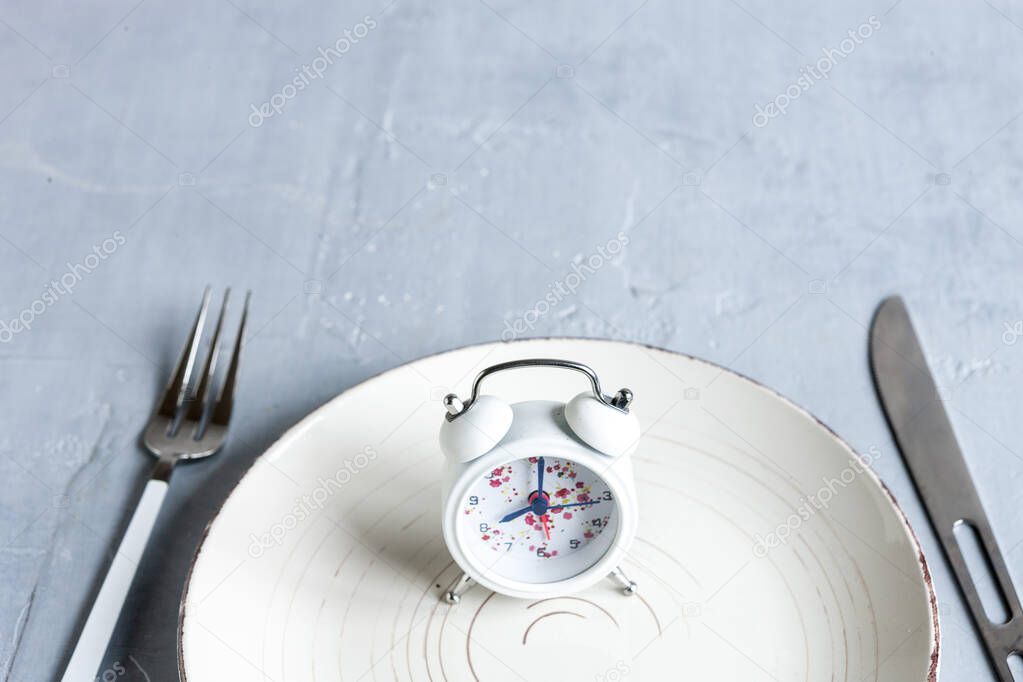 Alarm clock, White plate with fork and knife, Intermittent fasting concept, ketogenic diet, weight loss