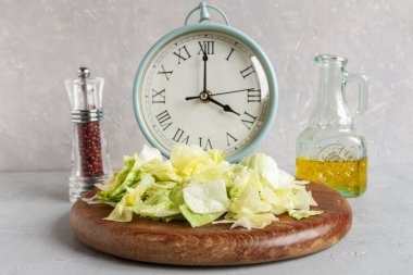 Çalar saat ve tabakta yeşil buzdağı marulu, zeytinyağı, aralıklı oruç kavramı, ketojenik diyet, kilo kaybı