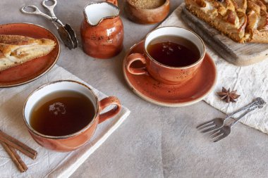 Elmalı turta, bir fincan kokulu çay, tarçın çubukları, anason ve tahta arka planda kırsal tarzda bıçak kesme.