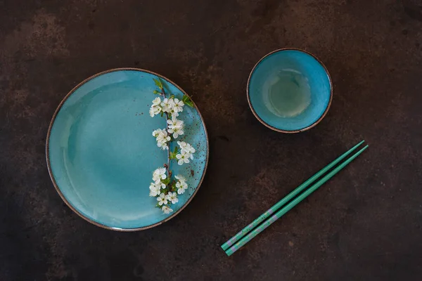 春花日本料理概念 蓝菜上有盛开的樱桃树枝条 深色背景上有筷子 — 图库照片