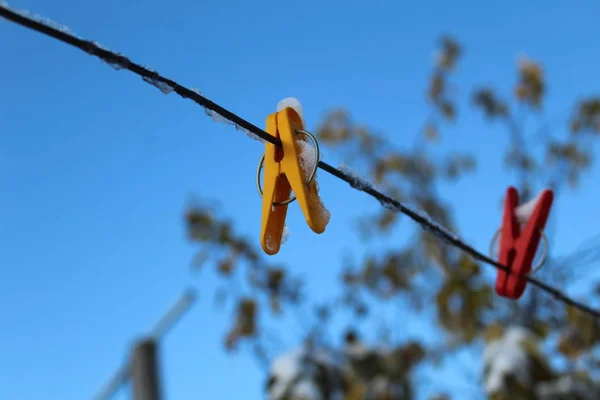 clothespins for drying clothes on a rope in the cold autumn / photo colored clothespins.they are attached to a clothesline.rope on the street in the yard.against a beautiful, bright blue sky.