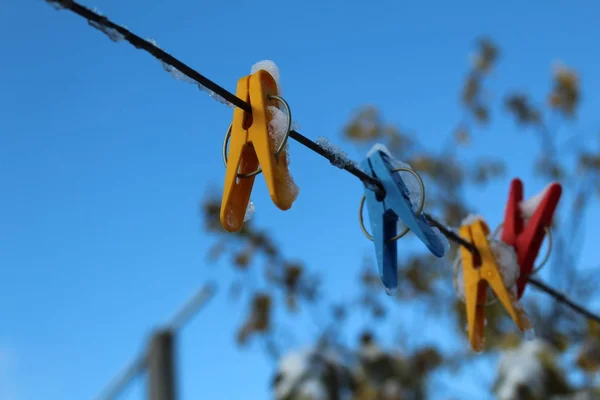 clothespins for drying clothes on a rope in the cold autumn / photo colored clothespins.they are attached to a clothesline.rope on the street in the yard.against a beautiful, bright blue sky.