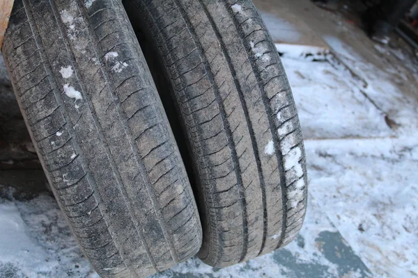 old tires from car in winter / photo of old car wheels. they are round, standing against the wooden wall of the garage.summer tires removed from the car.on the rubber protector.