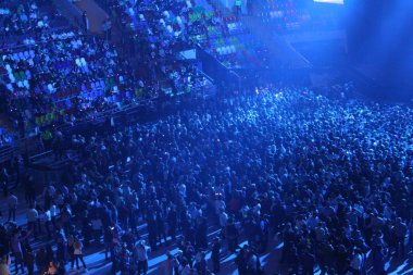 Konserdeki kalabalık, spor salonu, konser / fotoğraf spor kompleksi. Bir konsere ev sahipliği yapıyor. Koridorda bir sürü insan var. İnsanlar sandalyeye oturur ve platformda dururlar. Renkli ışıkların ışığında müzik eşliğinde dans etmek.