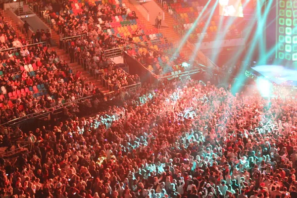 Konserdeki kalabalık, spor salonu, konser / fotoğraf spor kompleksi. Bir konsere ev sahipliği yapıyor. Koridorda bir sürü insan var. İnsanlar sandalyeye oturur ve platformda dururlar. Renkli ışıkların ışığında müzik eşliğinde dans etmek.