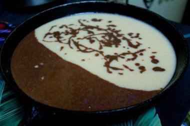 Bir turtayı dökme demir tavada pişirmek / fotoğraf pişirmek için bir turta hazırlamak. Dökme demir bir tavaya iki renk karışımı dökülür. Bir kısmı çikolata. Ev mutfağında tatlı pişirmek..