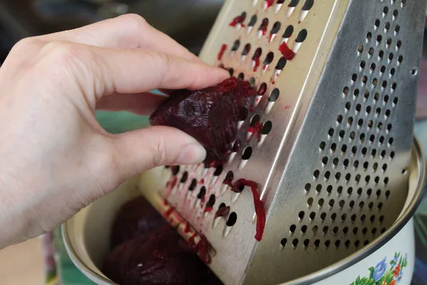 Metal rendeleyiciye kırmızı pancar ve foto metal rendeleyici koyun. Elini tabakta rendelenmiş kırmızı pancara sürt. Öğle yemeği, akşam yemeği ve kahvaltı..