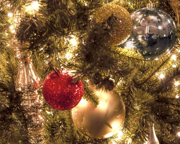 Yatay sıkı yakın çekim parlak ışıklar ve bu ilginç bir görüntü oluşturmak için ağaç dalları ile geleneksel bir Noel ağacı üzerinde asılı bir Noel süsler
