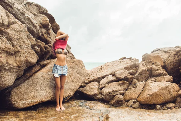 Sexy Mädchen ziehen sich am Felsstrand aus. — Stockfoto