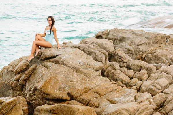 Beautiful girl in blue swimsuit sit on big stone. — Stock Photo, Image