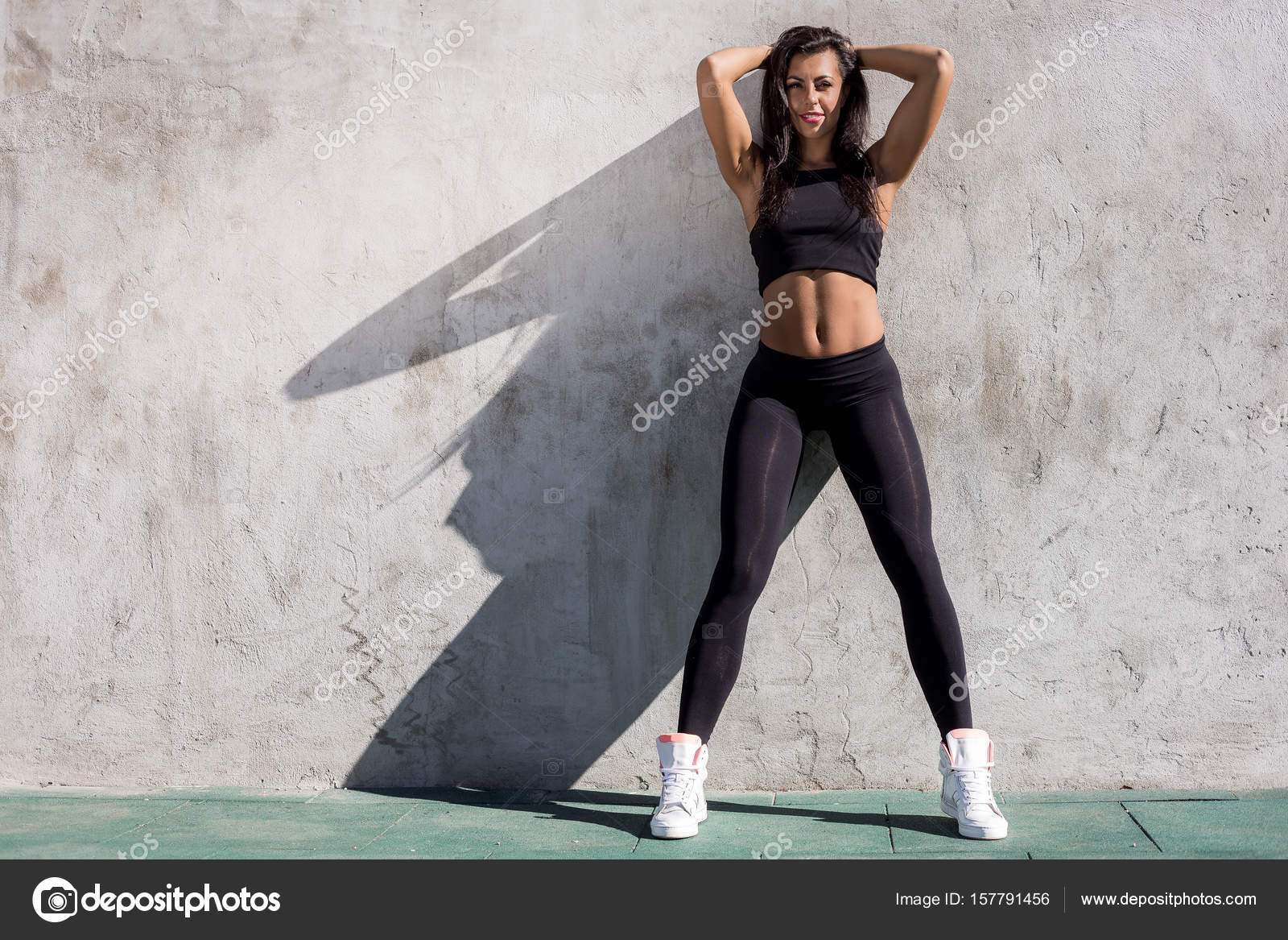 Beautiful young woman with long legs in bright sexy leggings with pretty  athlete muscular body sit with protein shaker. Crossfit training urban area  street gym city exercise routine healthy lifestyle. Stock Photo