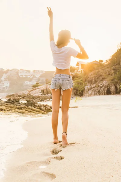 Chica en pantalones cortos a pie en la playa . — Foto de Stock