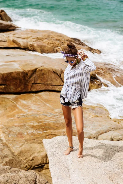 Vacker flicka på stor sten på stranden. — Stockfoto
