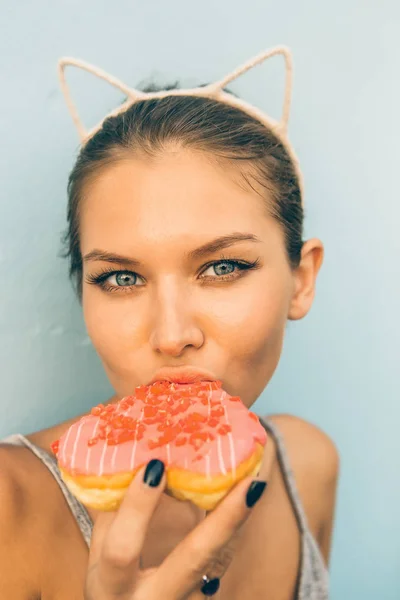 Sexy morena senhora comer doce coração em forma de donut . — Fotografia de Stock