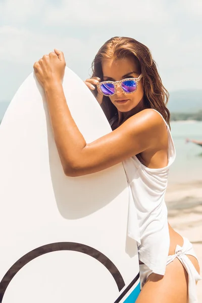 Sexy Mädchen am tropischen Strand mit Surfbrett. — Stockfoto