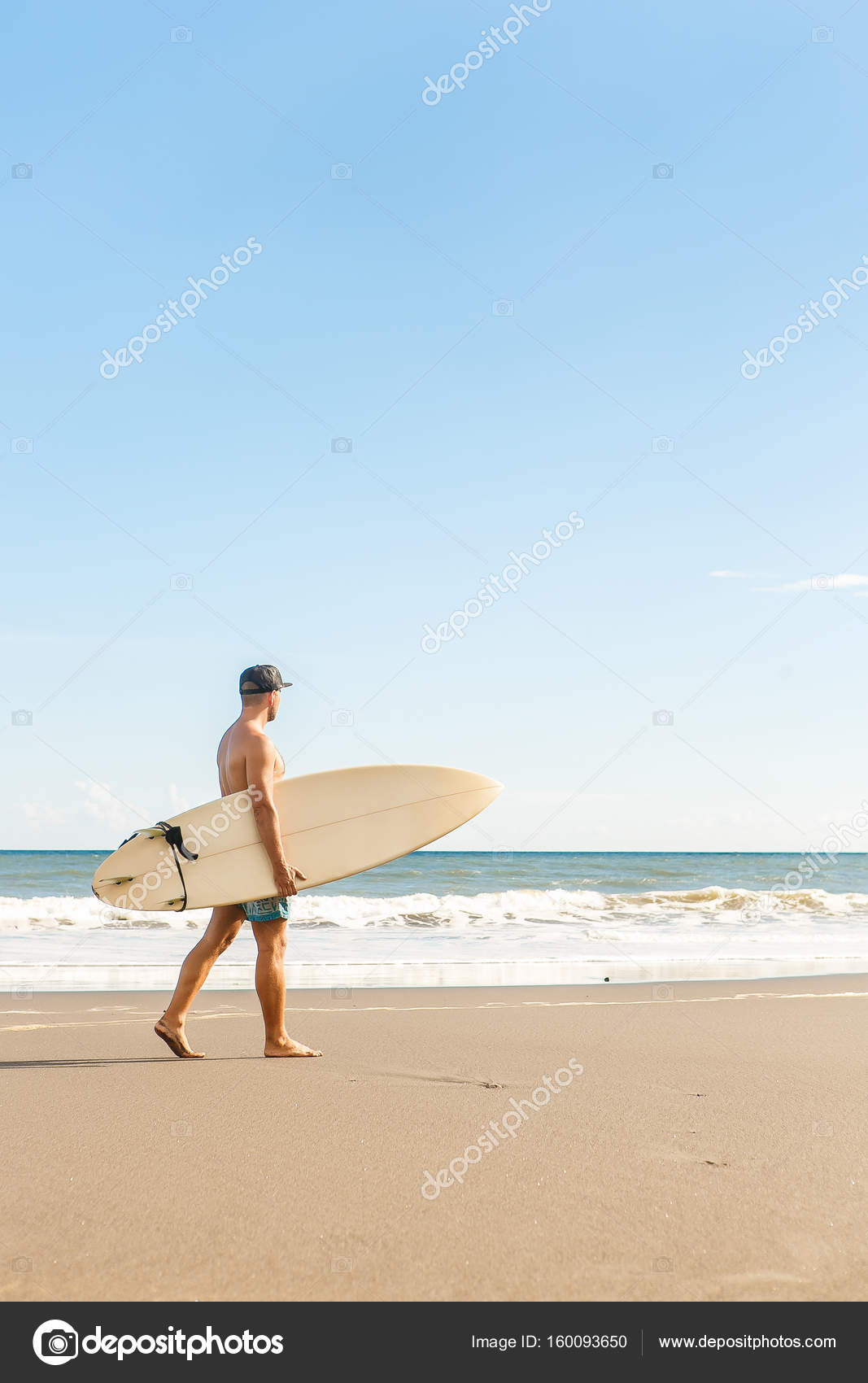 Handsome man with surfing board on spot.