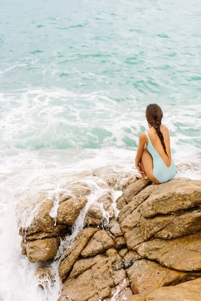 Menina bonita em maiô azul sentar-se em grande pedra . — Fotografia de Stock