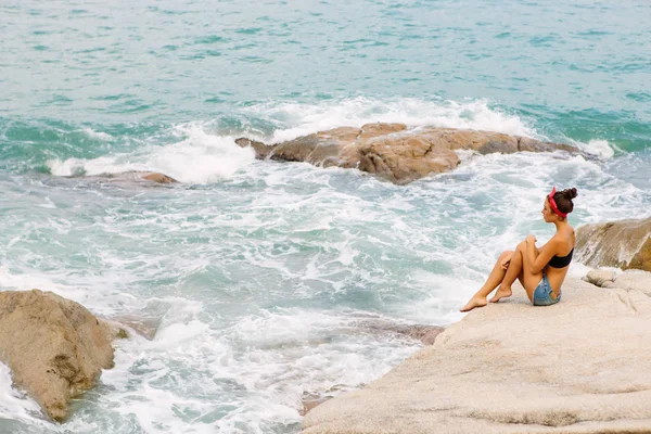 Menina bonita em shorts curtos sentar-se em grandes pedras . — Fotografia de Stock