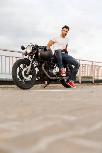 Brutale man zitten op café racer aangepaste motor. — Stockfoto