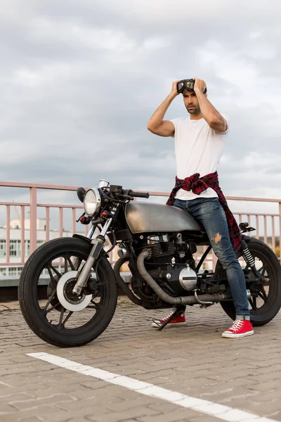 Brutální muž blízko jeho café racer vlastní motorka. — Stock fotografie