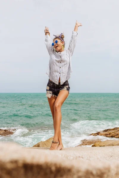 Mooi meisje op grote steen op het strand. — Stockfoto