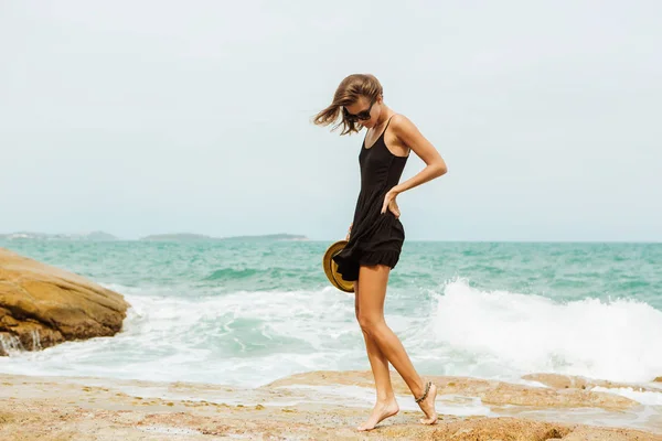 Nettes Mädchen im schwarzen Sommerkleid an großen Steinen. — Stockfoto