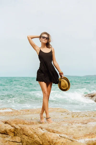Симпатичная девушка в черном летнем платье у больших камней . — стоковое фото