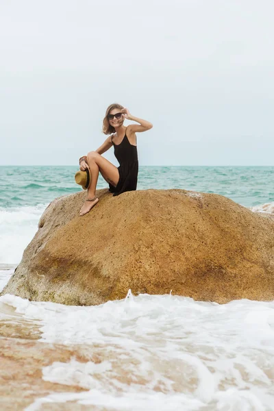 Linda chica en vestido de verano negro en piedras grandes . — Foto de Stock