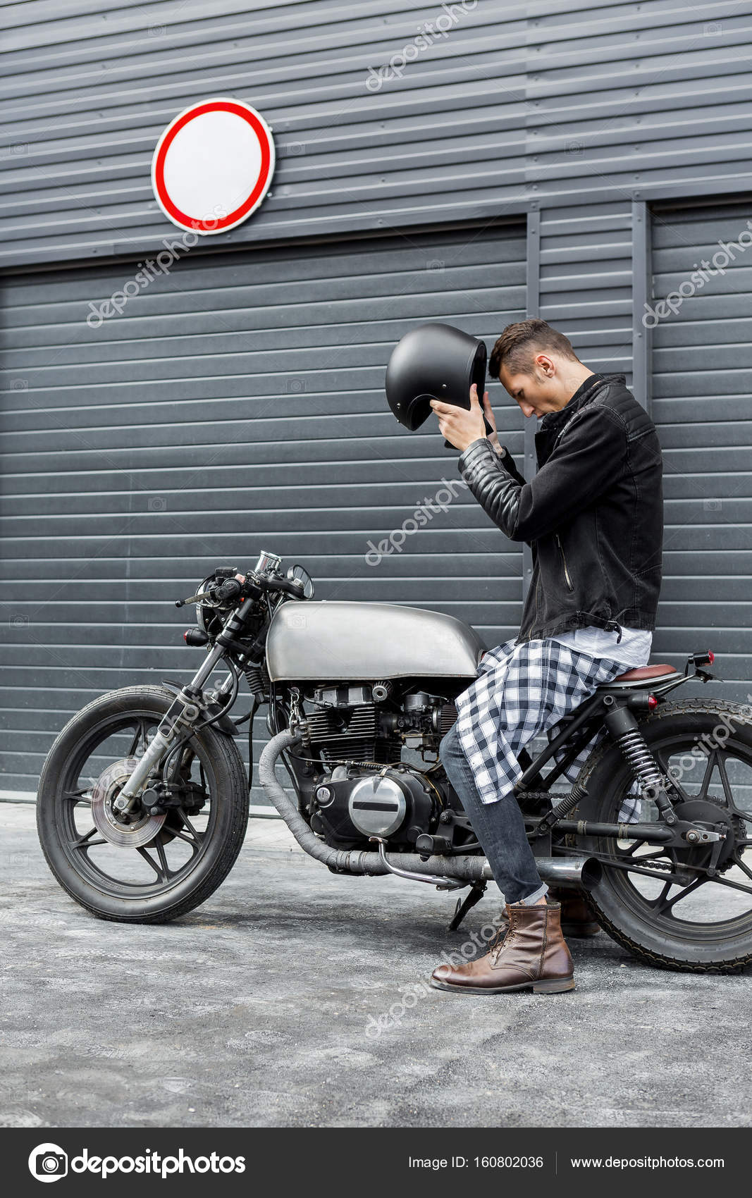 Handsome Rider Guy Take Off Black Biker Helmet While Sit On Classic Style Cafe Racer Motorcycle Near Industrial Gates Bike Custom Made In Vintage Garage