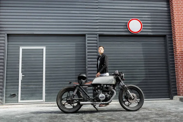 Brutal homem perto de seu piloto de café motocicleta personalizada . — Fotografia de Stock