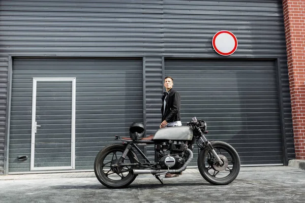 Brutalny mężczyzna w pobliżu jego café racer motocykl niestandardowe. — Zdjęcie stockowe