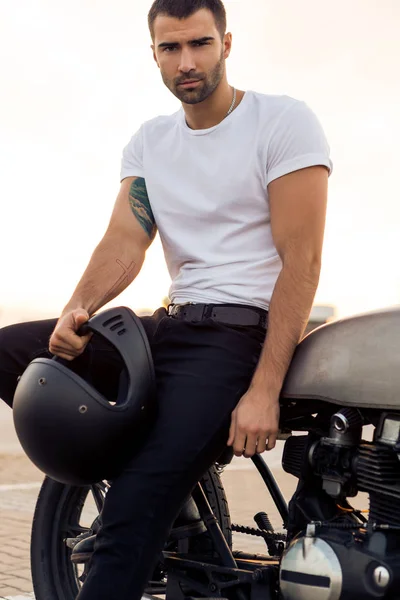 Brutal man sit on cafe racer custom motorbike.