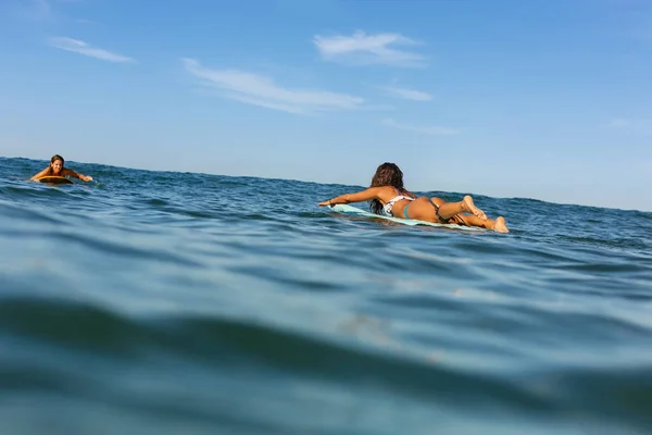 Dvě krásné sportovní dívky surfování v oceánu. — Stock fotografie