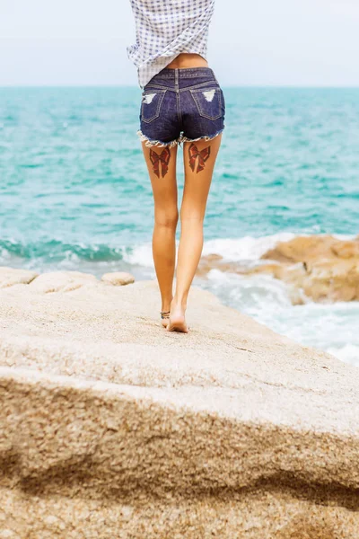 Mooi meisje op grote steen op het strand. — Stockfoto