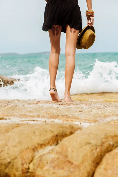 Schattig meisje in zwarte zomer jurk op grote stenen. — Stockfoto